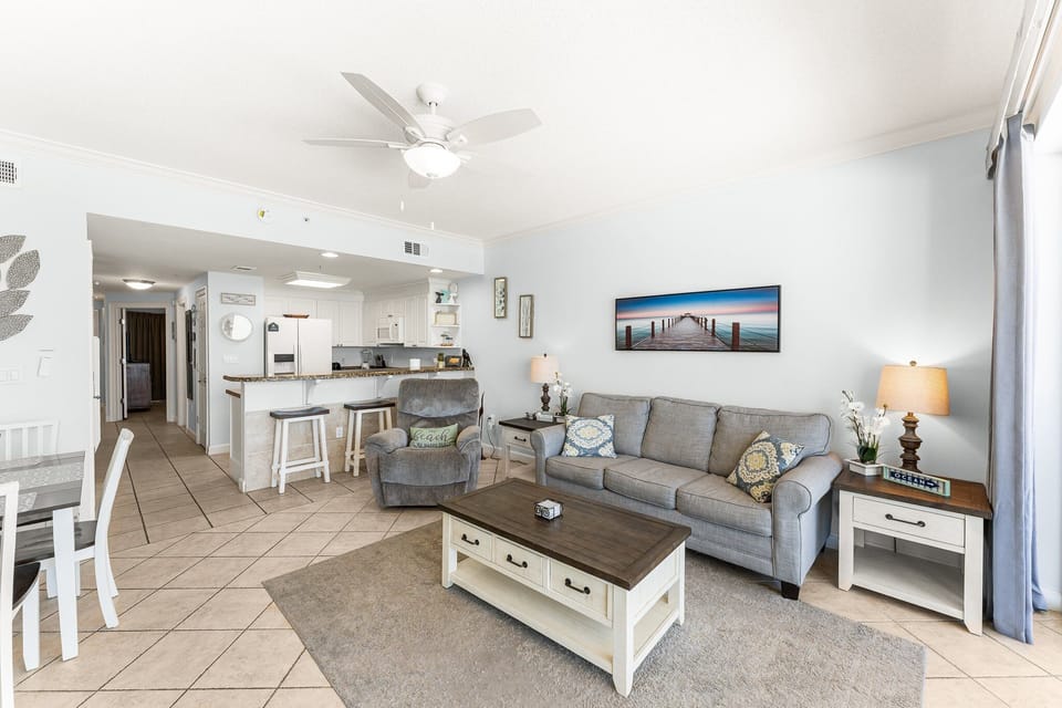 The living room offers ample, comfortable seating with expansive views of the Gulf of Mexico, a large flat screen television, and access to the unit's private balcony.