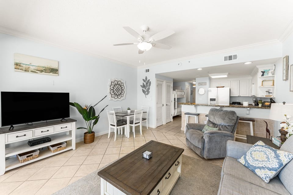 The living room offers ample, comfortable seating with expansive views of the Gulf of Mexico, a large flat screen television, and access to the unit's private balcony.
