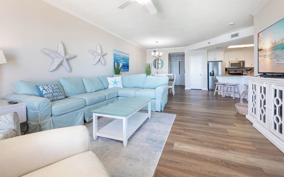 Unwind in the airy living space featuring a large sectional sofa, coastal decor, and a flat-screen TV