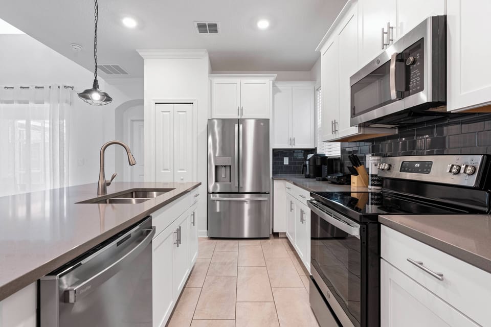Welcome to this stylish kitchen with stainless steel appliances and a sleek dark countertop that pairs beautifully with the white cabinetry.