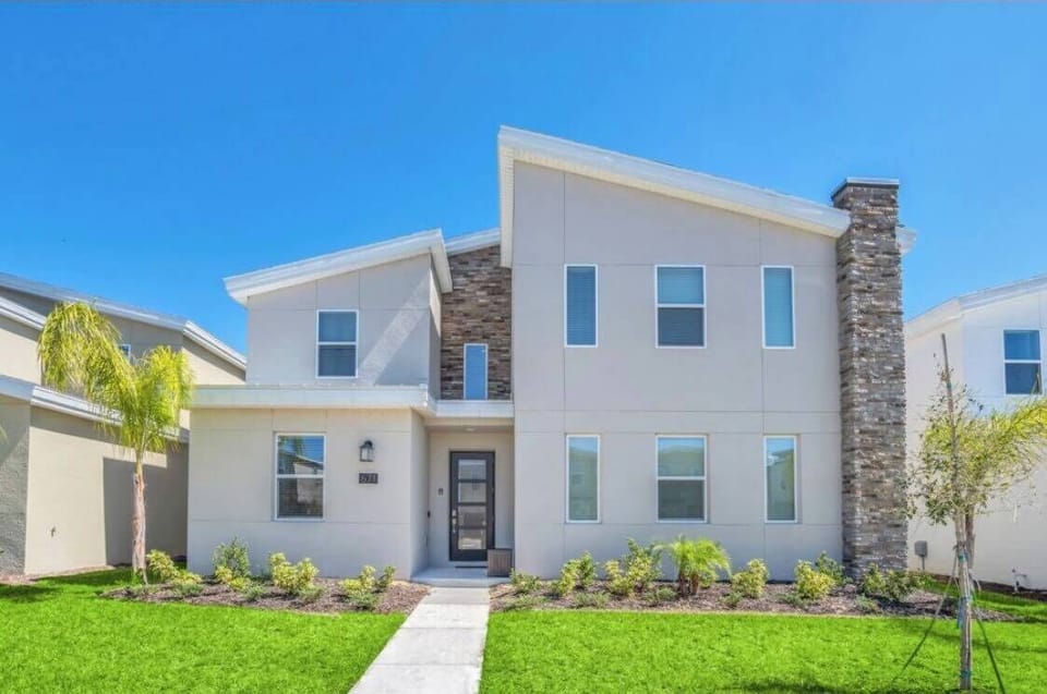 Experience a charming exterior with light-colored siding and striking stone accents, surrounded by beautifully landscaped greenery. Large windows invite plenty of natural light, making for a bright and welcoming atmosphere.