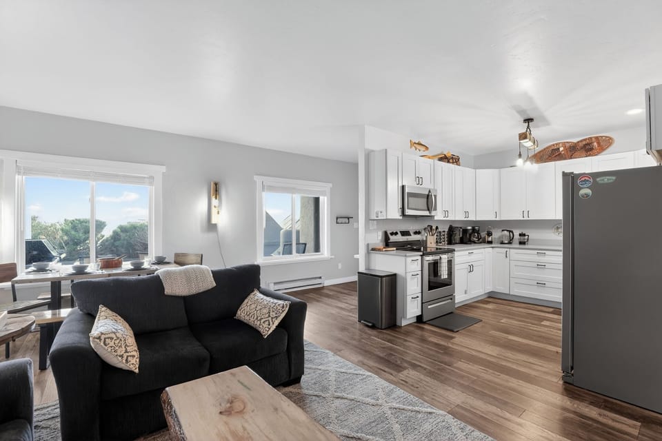 Bright open living space with modern kitchen and large sunny windows. New handmade beetle kill coffee table.