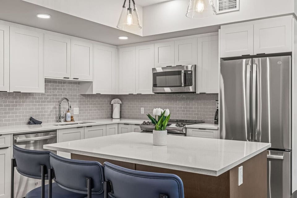Fabulous, ultra-modern kitchen with all white cabinets, white quartz countertops, and an oversized kitchen island