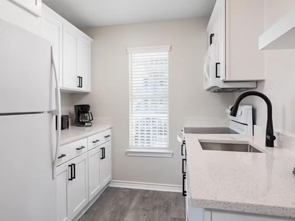 Bright kitchen with white cabinetry, full-size appliances, and plenty of counter space for cooking