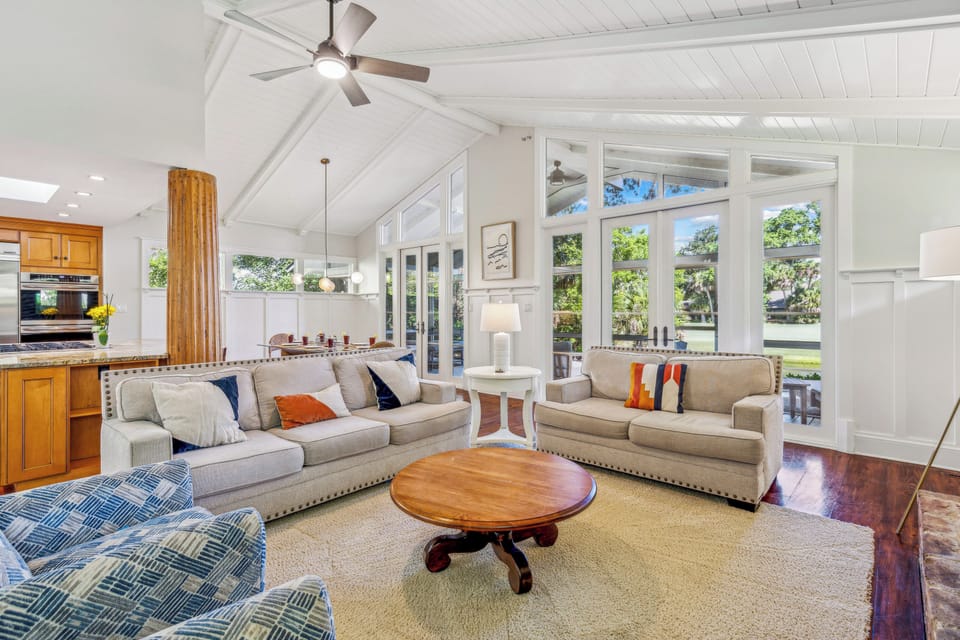 Natural light floods the space from vaulted ceilings and numerous windows, creating an inviting atmosphere perfect for relaxation and enjoying each other's company.