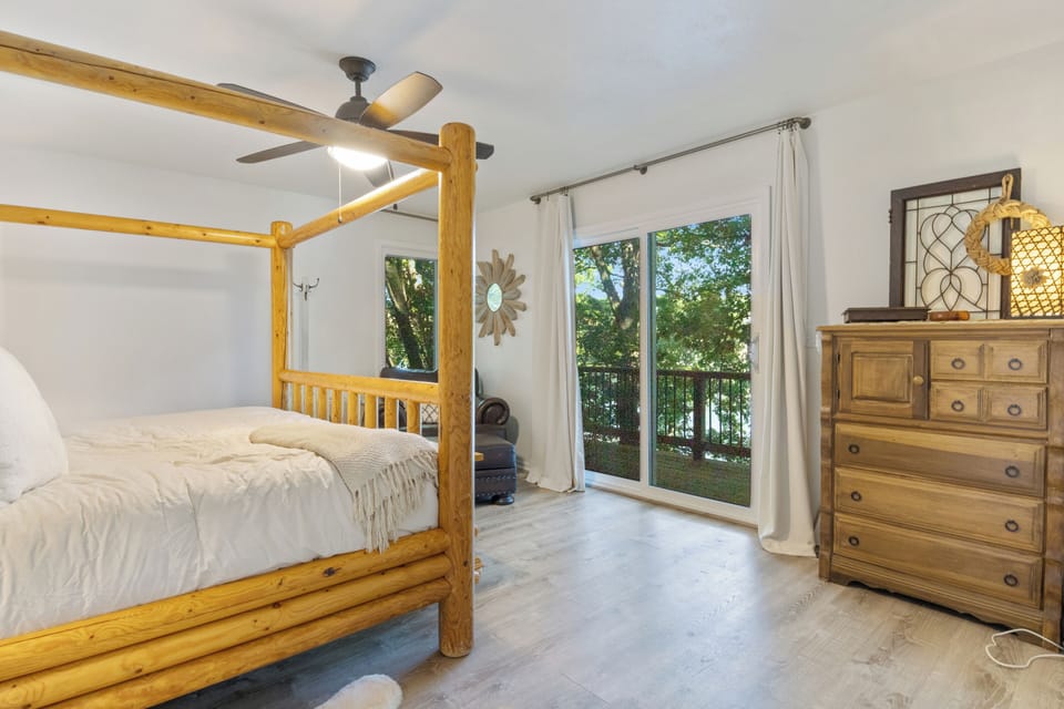 Spacious bedroom with a log frame bed, natural light, and balcony access