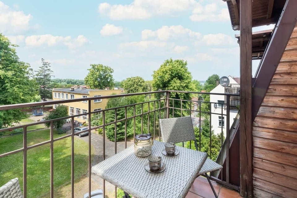 A balcony featuring a small round table and chairs, overlooking greenery.

