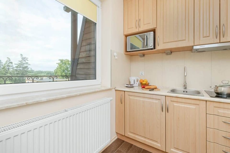 A bright galley kitchen with upper and lower cabinets and a scenic window.

