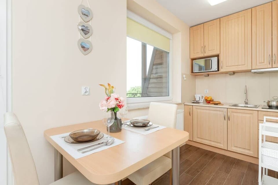 A light kitchen with wooden cabinets and a small dining table for two.

