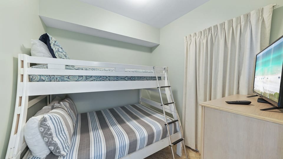 Your kids will love this cozy bunk bed setup with crisp linens and their own TV for bedtime stories.