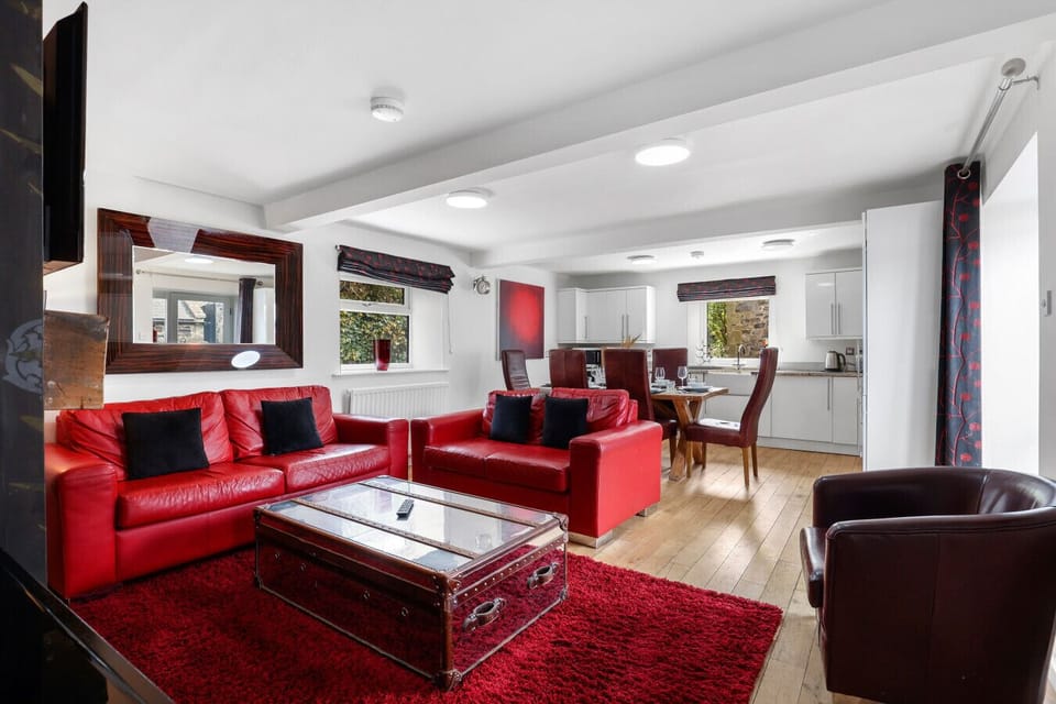Open-plan lounge with red leather sofas and oak flooring