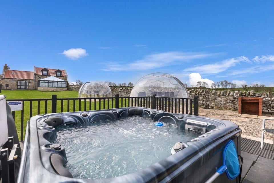 Shared hot tub overlooking the lawn with garden pods and paddock