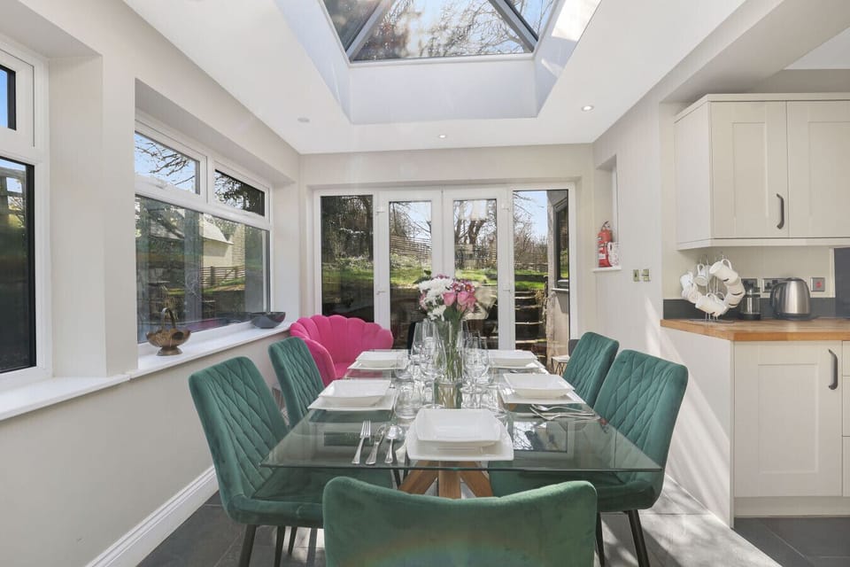 Dining area with velvet chairs beneath a glazed roof lantern