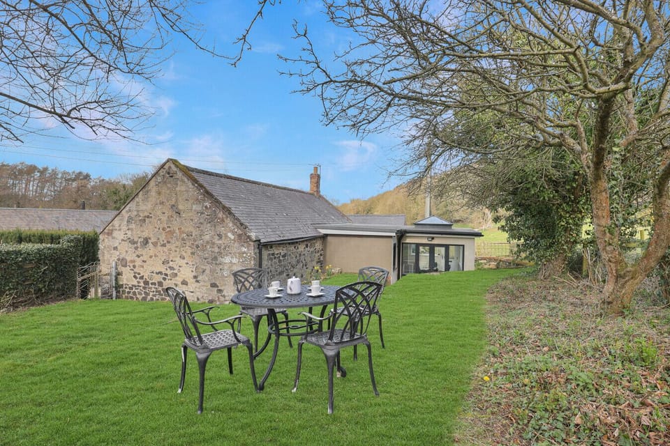 Lawn garden with cast-iron dining set beside the stone cottage