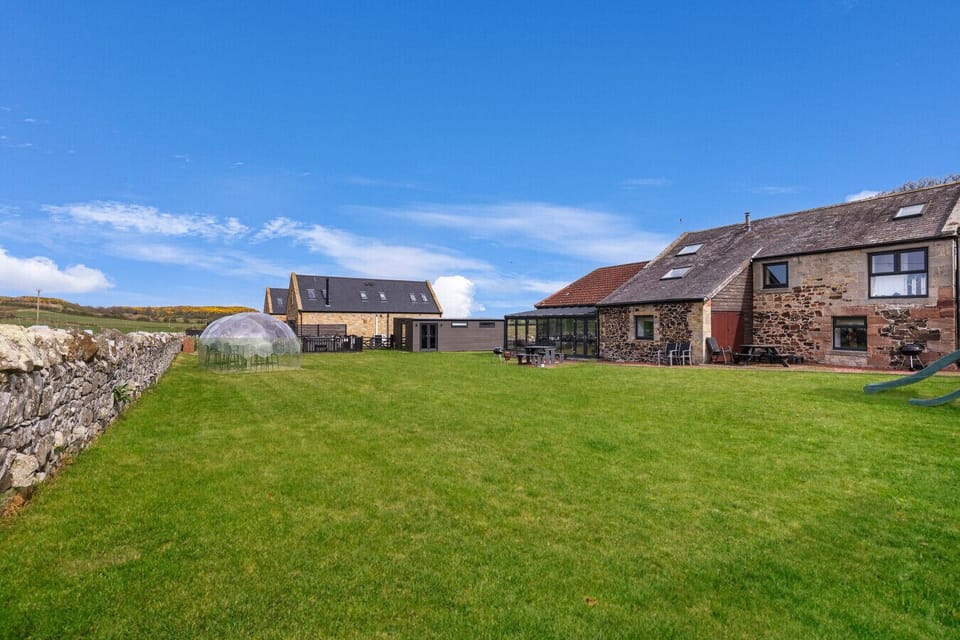 Large shared grass paddock with stone cottages and garden domes.