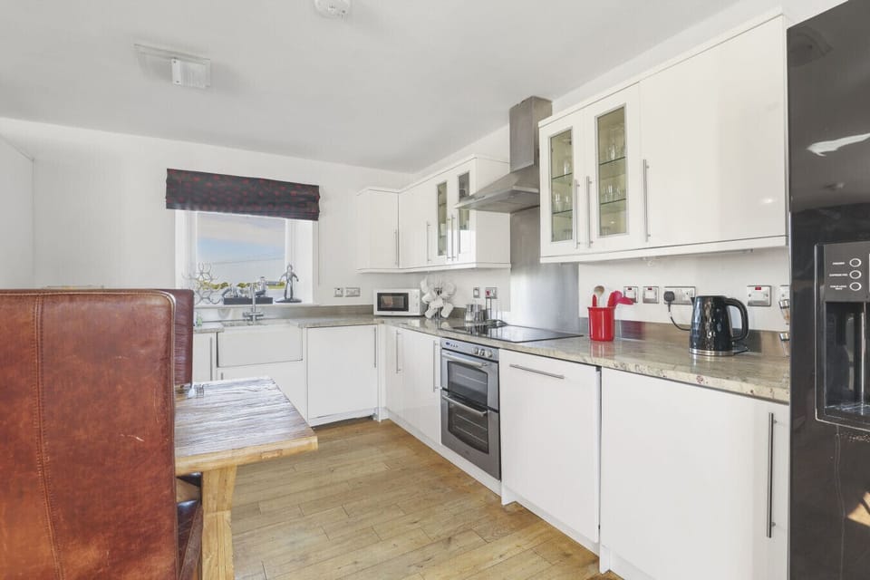 Bright, cozy kitchen with white cabinetry and timber flooring.