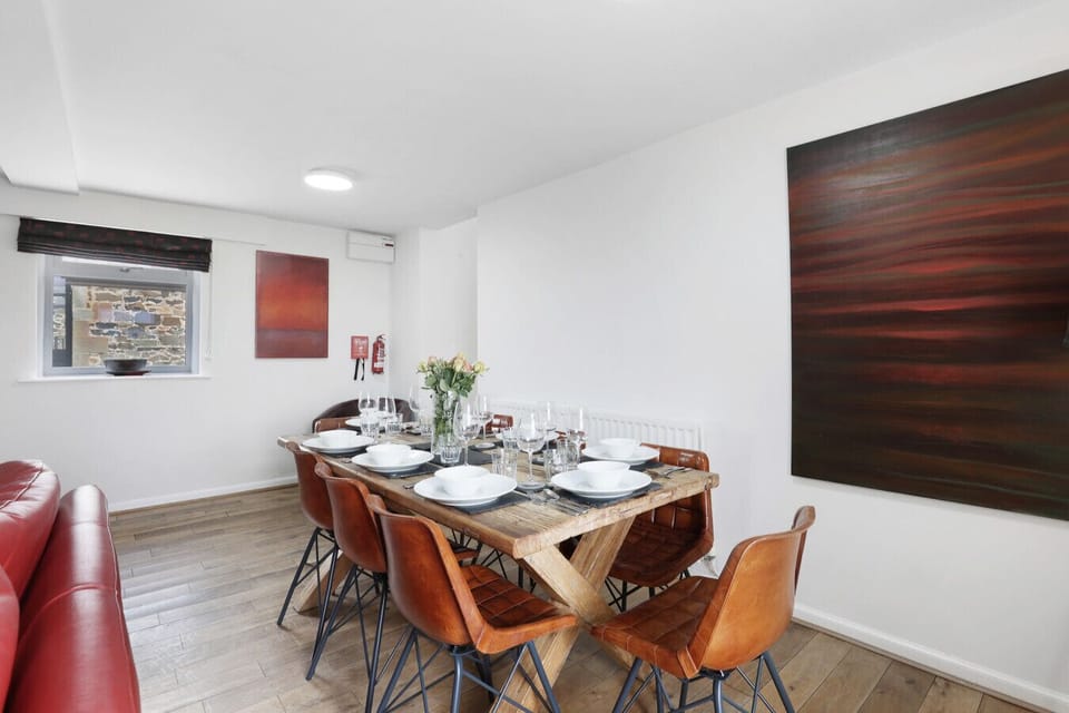 Dining area with timber table and leather chairs beside lounge.