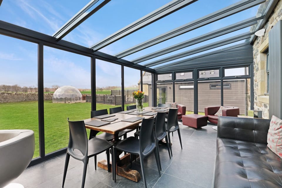 Conservatory dining area with glass roof and garden views