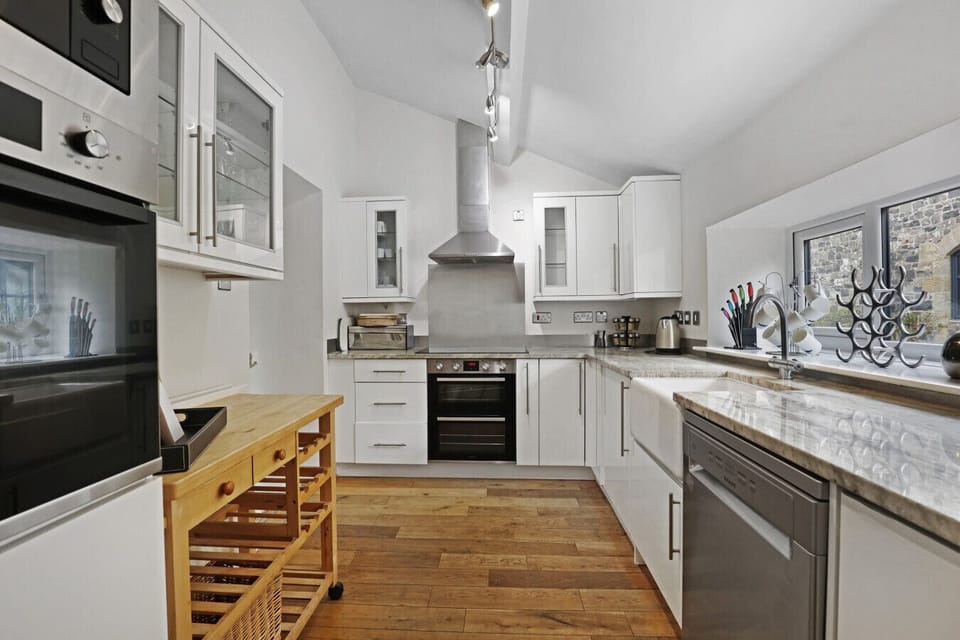 White kitchen with marble-effect worktops and oak flooring