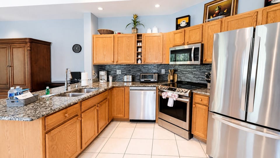 Updated kitchen with granite countertops, stainless steel appliances, cabinet storage, and tile flooring.