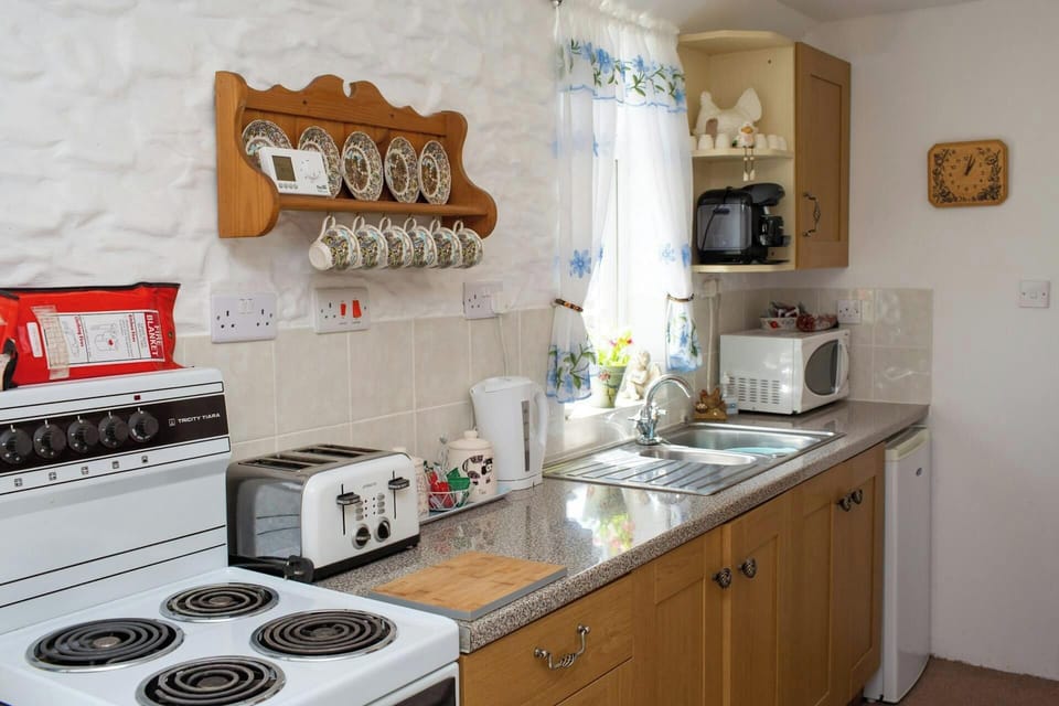 Electric cooker. Base cupboards and window above sink, kettle, toaster, microwave and fridge