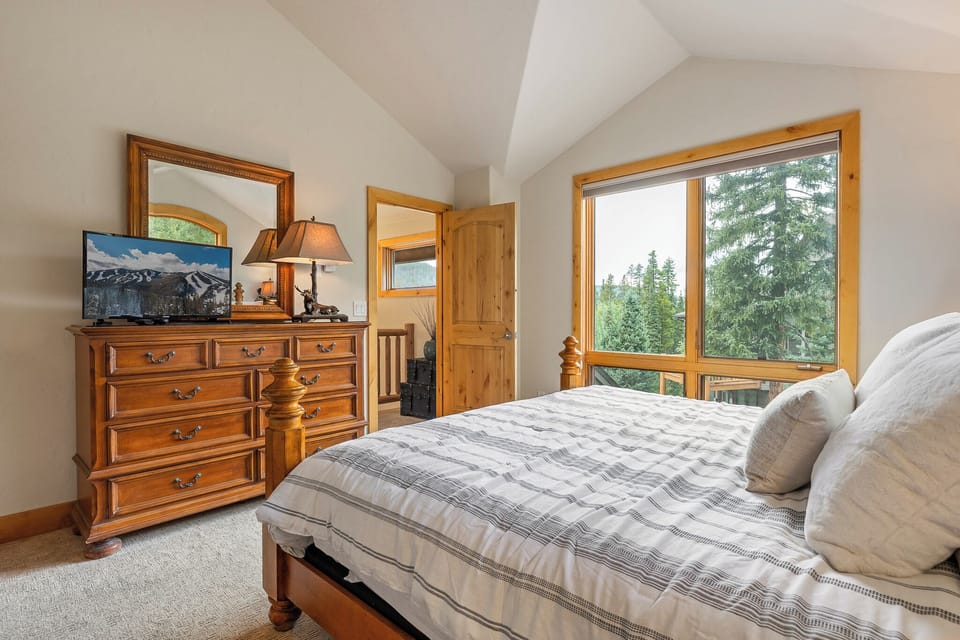 Bedroom with large window bringing in natural forest views   - Cozy bedding and dresser provide comfort during mountain stay   - Bright relaxing space ideal for peaceful nights and mornings