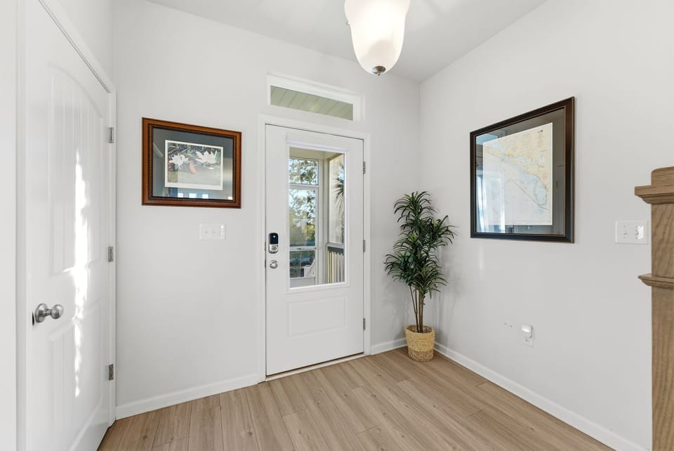 Your bright entryway welcomes you with warm wood floors, coastal artwork, and a cheerful plant—the perfect start to your getaway.