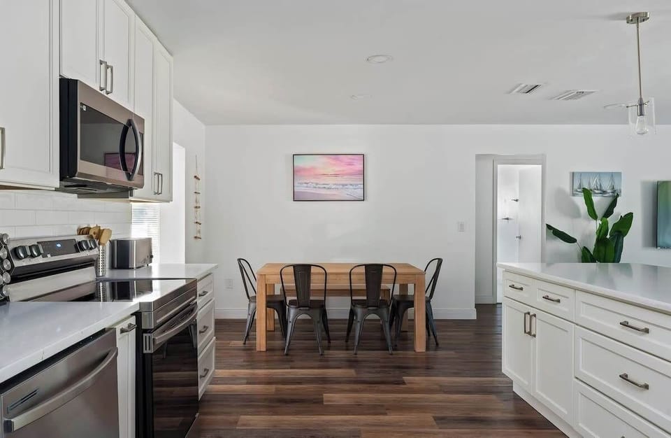 Spacious open-concept kitchen and dining area perfect for gathering! Enjoy crisp white cabinetry, stainless steel appliances, ample counter space, and warm wood floors. The dining table is steps away ideal for family meals, and easy everyday living.