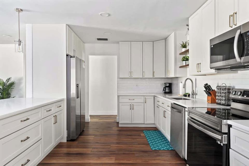 Beautifully updated—this kitchen shines with crisp white cabinetry, stainless steel appliances, and warm wood floors. Plenty of counter space and smart storage make cooking effortless, while the clean modern design is perfect for entertaining.