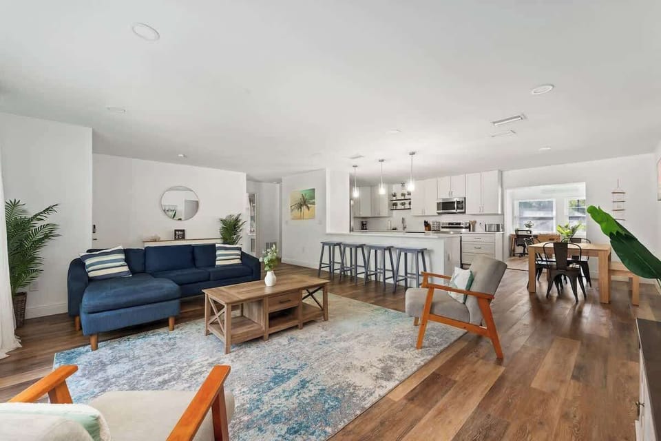 Step into this bright, open-concept living space featuring stylish furnishings, warm wood floors, and seamless flow to the kitchen and dining area. Perfect for entertaining or relaxing, with modern finishes, ample seating.