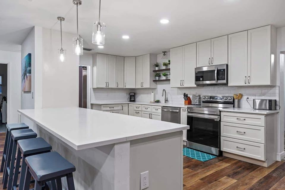 Sleek, modern kitchen designed for cooking and gathering! Featuring crisp white cabinetry, stainless steel appliances, stylish pendant lighting, and a spacious island with seating. Bright, open, and beautifully finished.