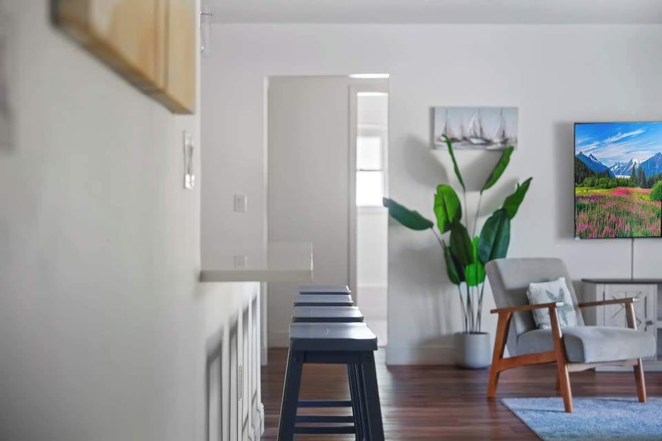 This open layout features a spacious breakfast bar with seating, warm wood floors, and stylish décor throughout. Perfect for morning coffee, casual meals, or hosting guests with effortless flow from kitchen to living space.
