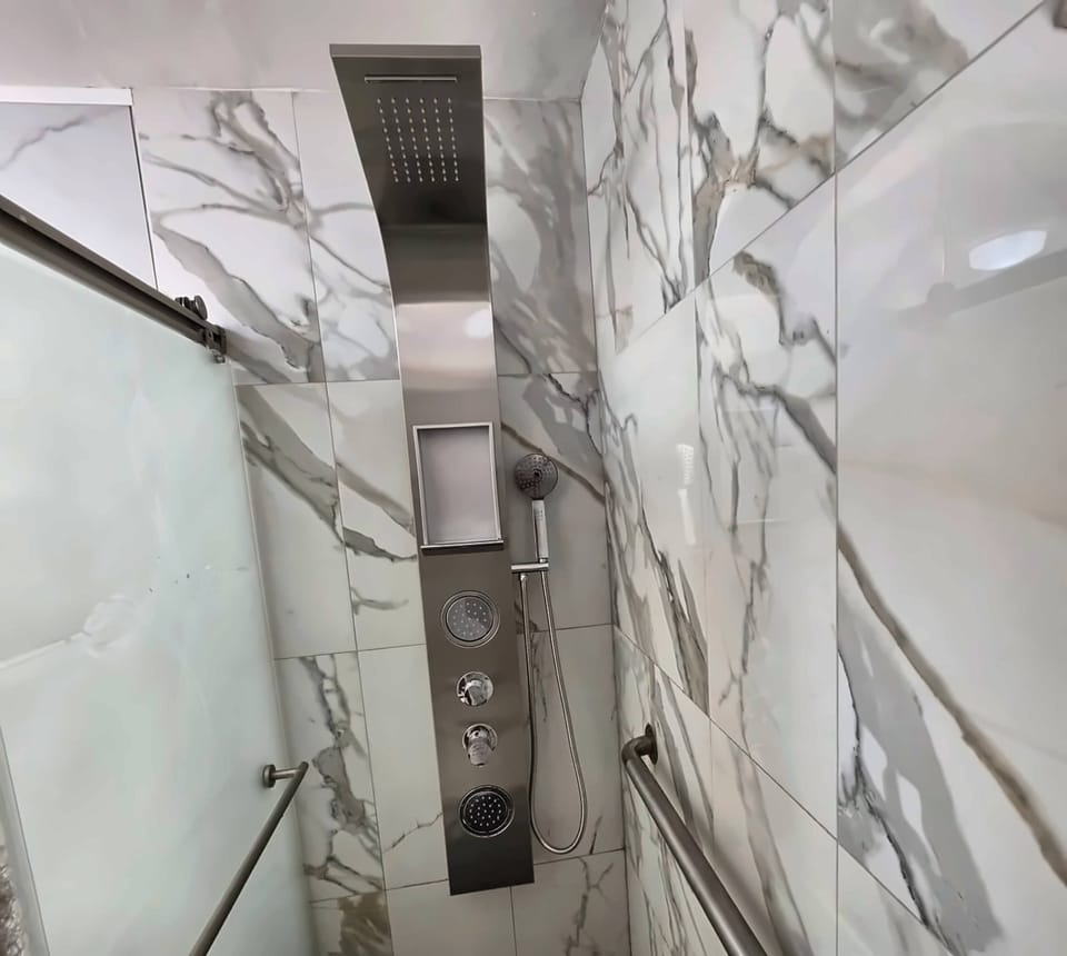 Rain shower with marble-look tiles.