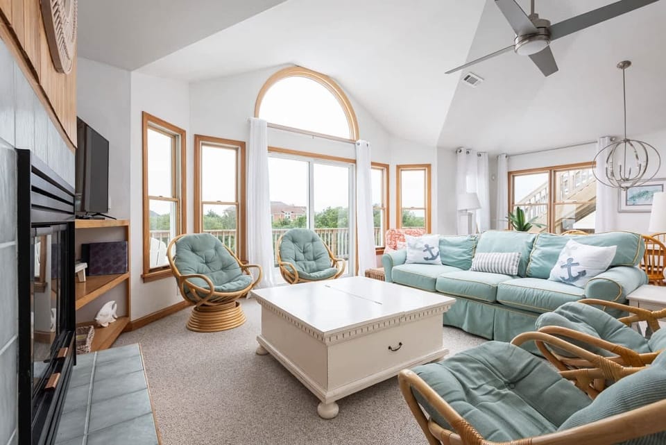 Sunlit Living Room w/ Vaulted Ceiling, Arched Picture Window, Mint Sectional Sofa, Swivel Lounge Chairs, White Coffee Table & Fireplace Feature