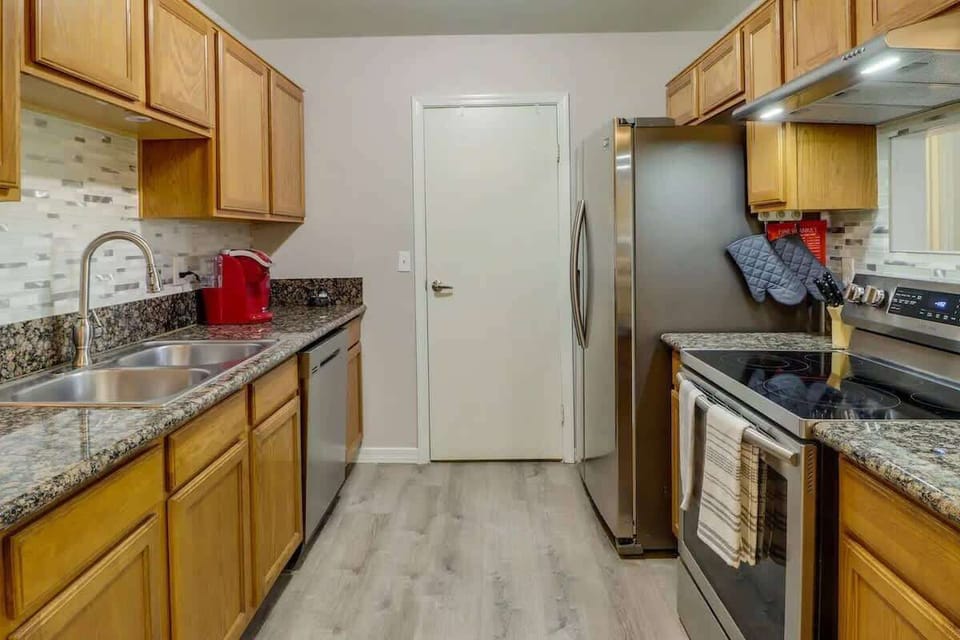 Cook with room to spread out on granite counters, with warm wood cabinets, tile backsplash, and a stainless range/microwave. Brew coffee beside the sink, plate it up, and head out the door with an easy meal plan.