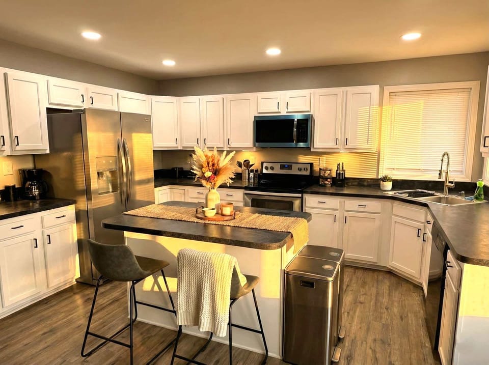 Kitchen with stainless steel appliances, white cabinetry, and breakfast bar seating.