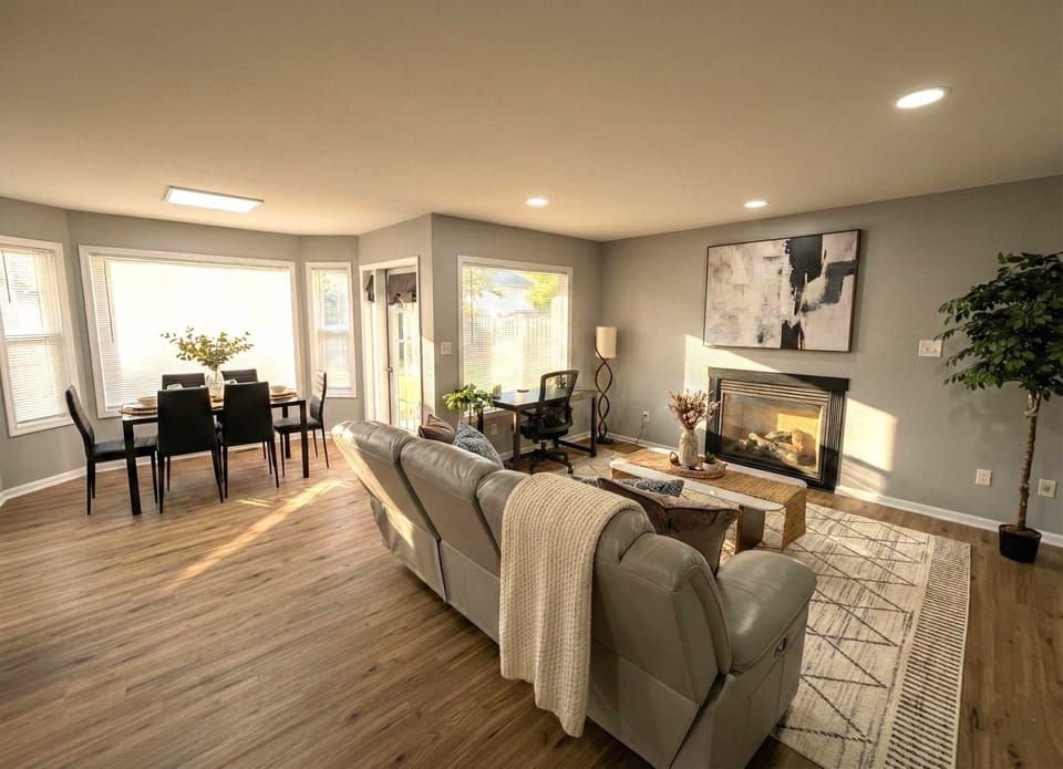 Living and dining area with sofa seating, fireplace, TV, dining table, and natural light.