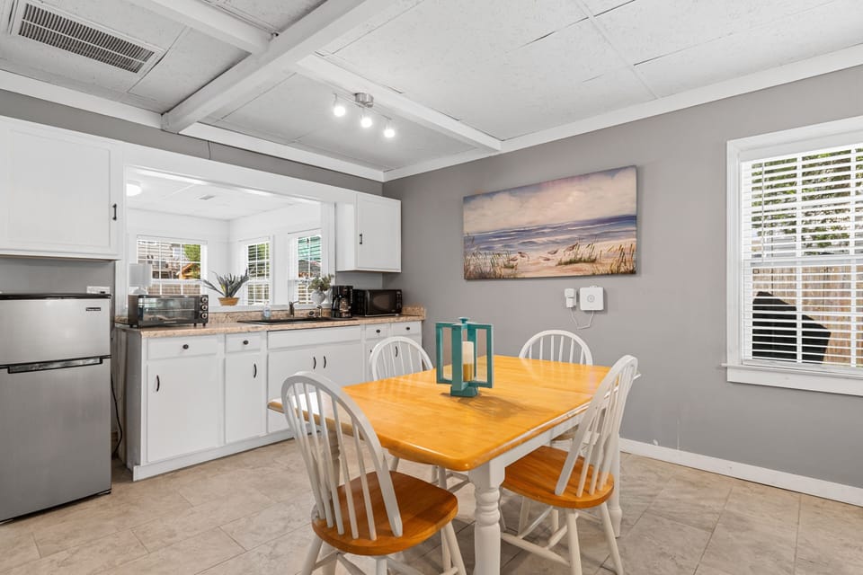 Gather around your private dining table in this bright kitchen space, where coastal artwork and warm wood tones create the perfect atmosphere for memorable meals together.