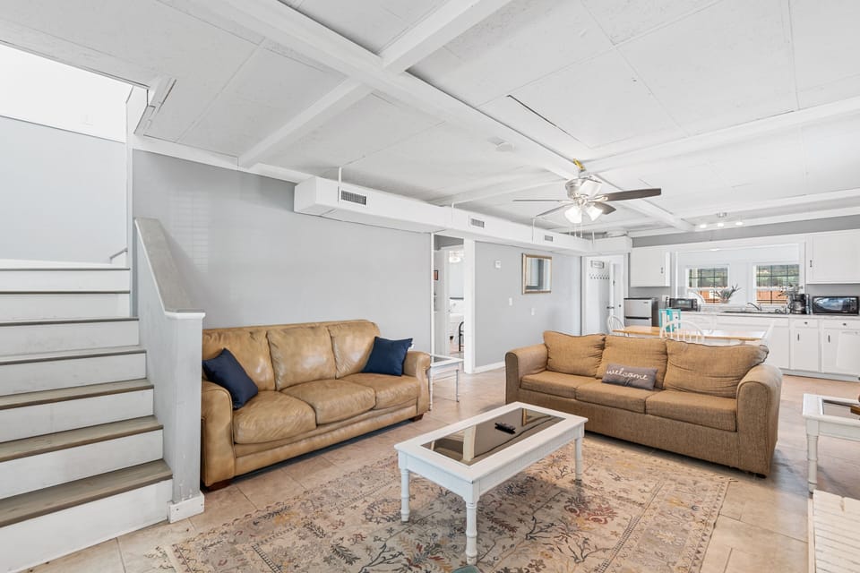 Relax in your spacious living area with comfortable leather seating, exposed beam ceilings, and an open kitchen perfect for entertaining.