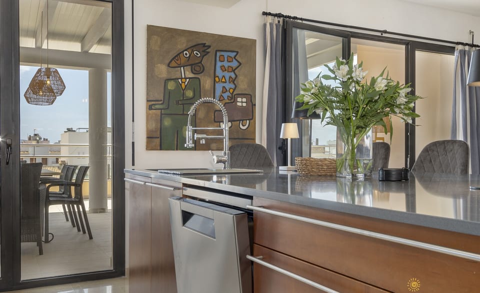 Modern kitchen with a stylish island and designer faucet, featuring plenty of natural light and direct access to the outdoor terrace and dining area.