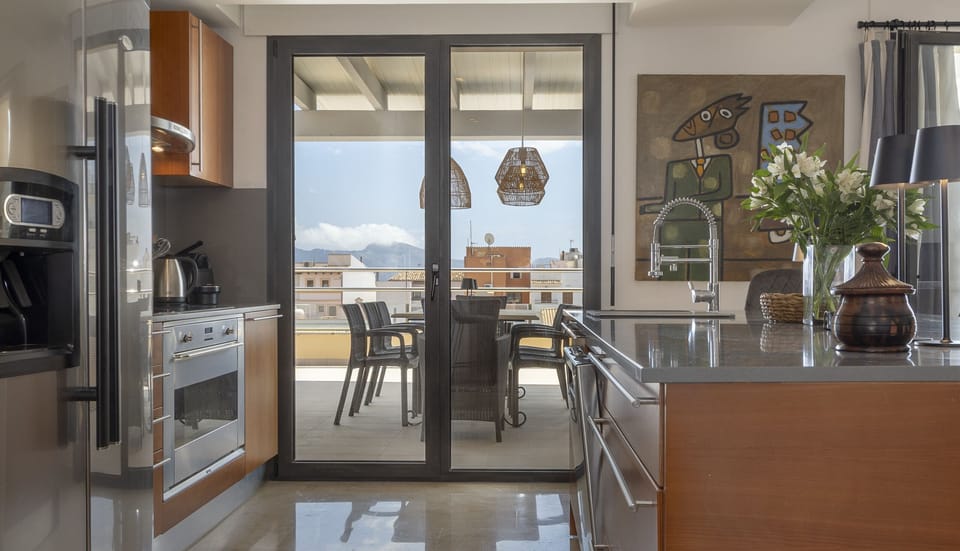 Bright kitchen with integrated appliances and direct access to the outdoor terrace, offering beautiful mountain views.