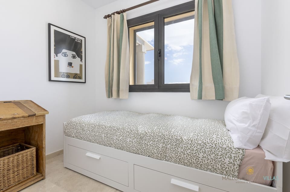 Cozy single bedroom with a trundle bed, natural light from the window, and rustic-style furniture, perfect for a comfortable stay.