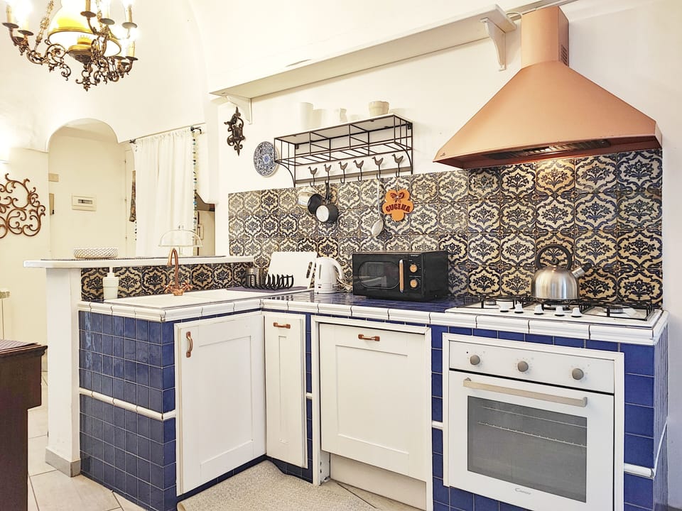 Cucina stile siciliano, balcone, frigo, congelatore, forno, microonde e caffè.