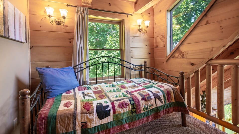 Charming bed with a colorful quilt and a storybook cabin feel.