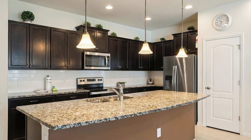 Spacious kitchen with granite island, dark wood cabinetry, and stainless appliances.
