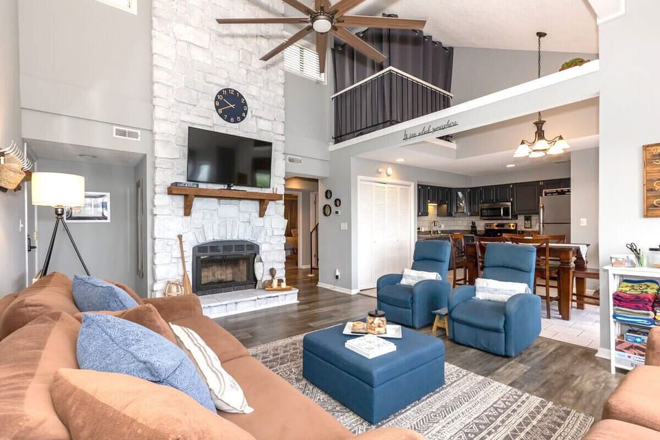 Cozy living space features large windows with beautiful water views and comfortable seating. The open floor plan connects the living area, dining space, and kitchen, making it perfect for relaxing getaways or gatherings.