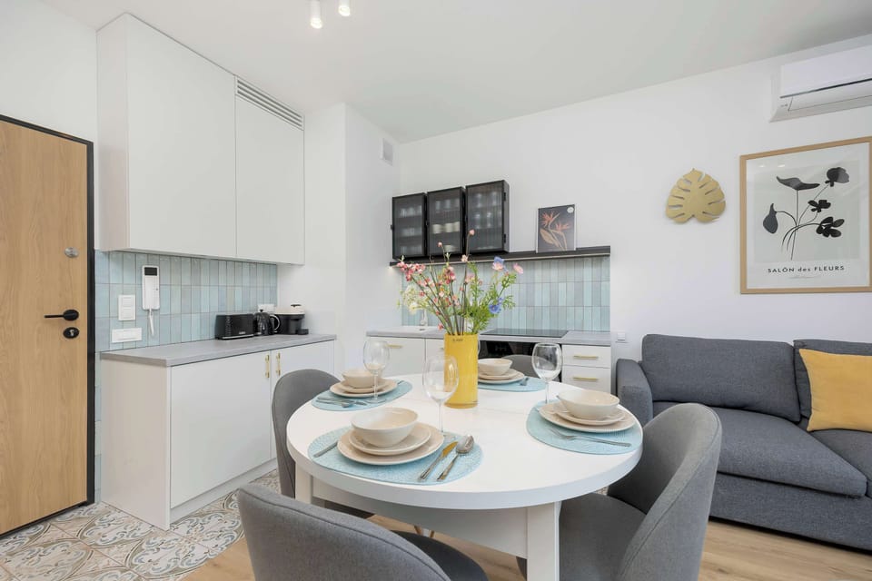 A modern kitchen and dining area with sleek cabinetry and a comfortable sofa in view.