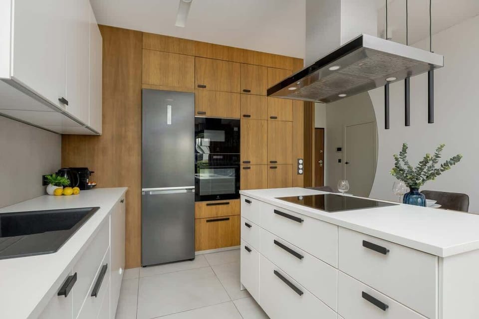 A modern kitchenette with white cabinets, a wooden countertop, and elegant appliances invites you to cook.