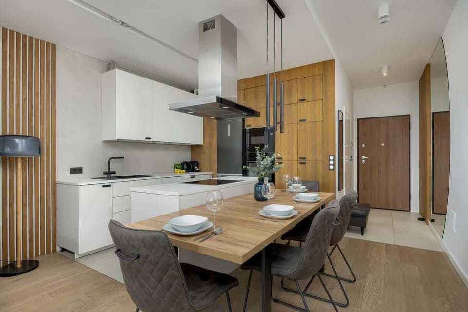 A modern kitchenette with wooden accents, an elegant table, and designer chairs is perfect for shared meals.