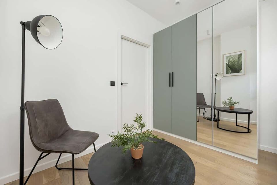 A minimalist bedroom with a bright interior, simple desk, and large mirror is perfect for work and rest.